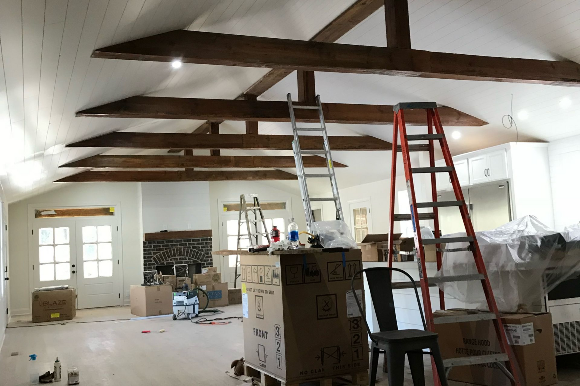 Man installing a recessed ceiling light in a modern kitchen with recessed lighting and glossy white cabinets.