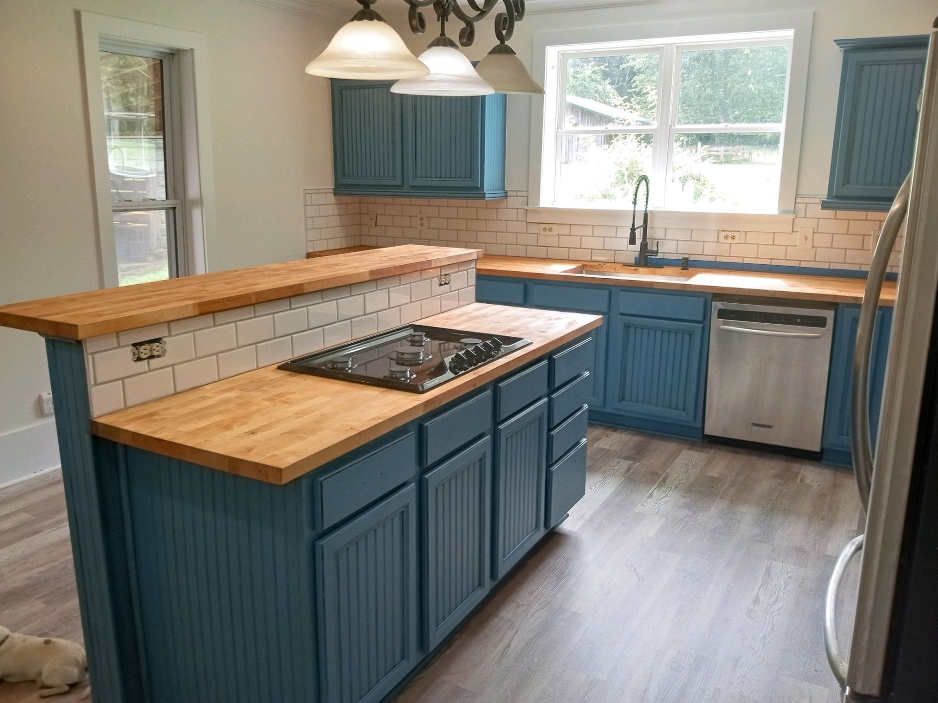 Kitchen under construction: Light wood cabinets, large window, boxes of supplies on the floor.