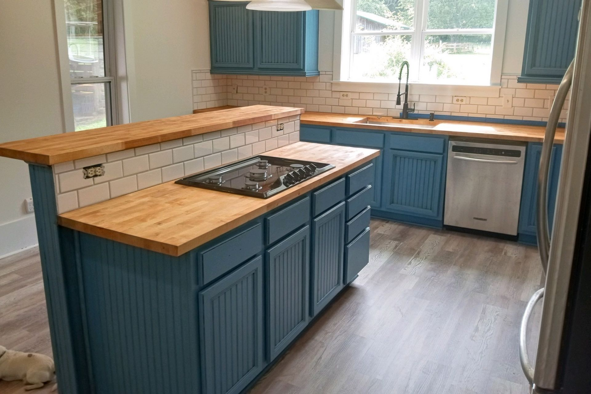 Kitchen under construction: Light wood cabinets, large window, boxes of supplies on the floor.