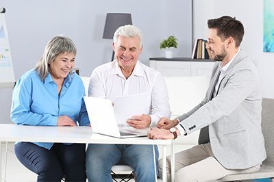A man and a woman are sitting at a table with a laptop.