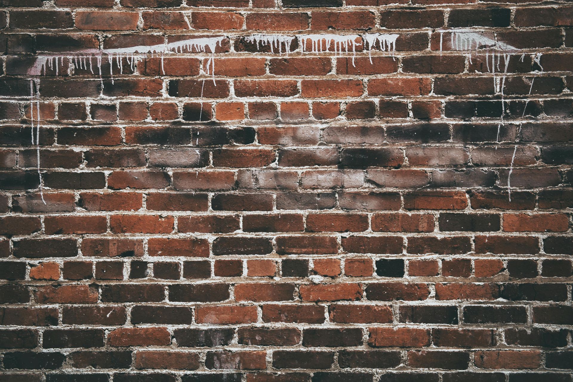 Red brick wall with dark patches, white drips from above.