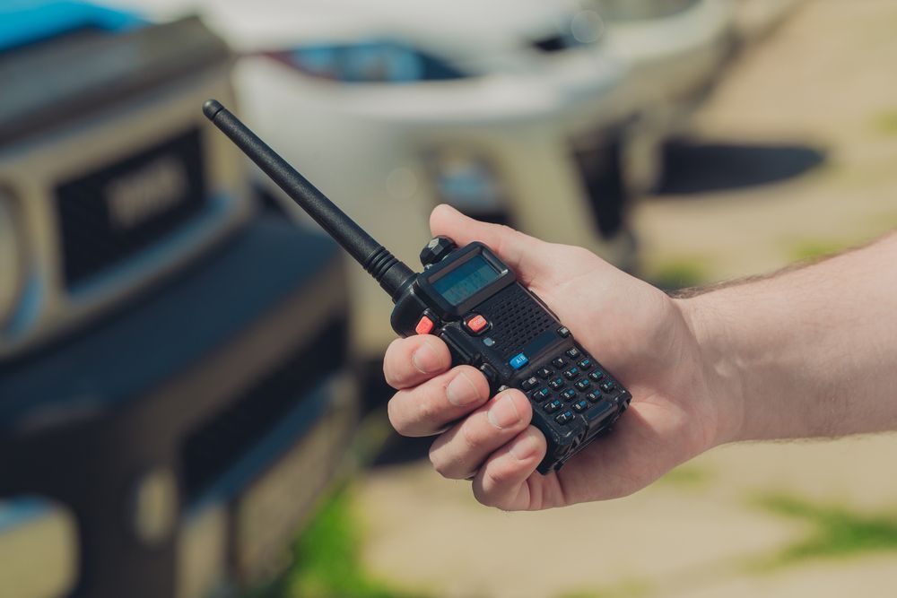 A Person is Holding a Walkie Talkie in Front of a Car — Outlaw Mechanical & Performance In Inverell, NSW