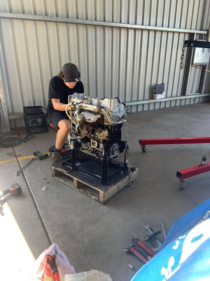 A Man is Sitting on a Pallet Working on a Machine — Outlaw Mechanical & Performance In Inverell, NSW