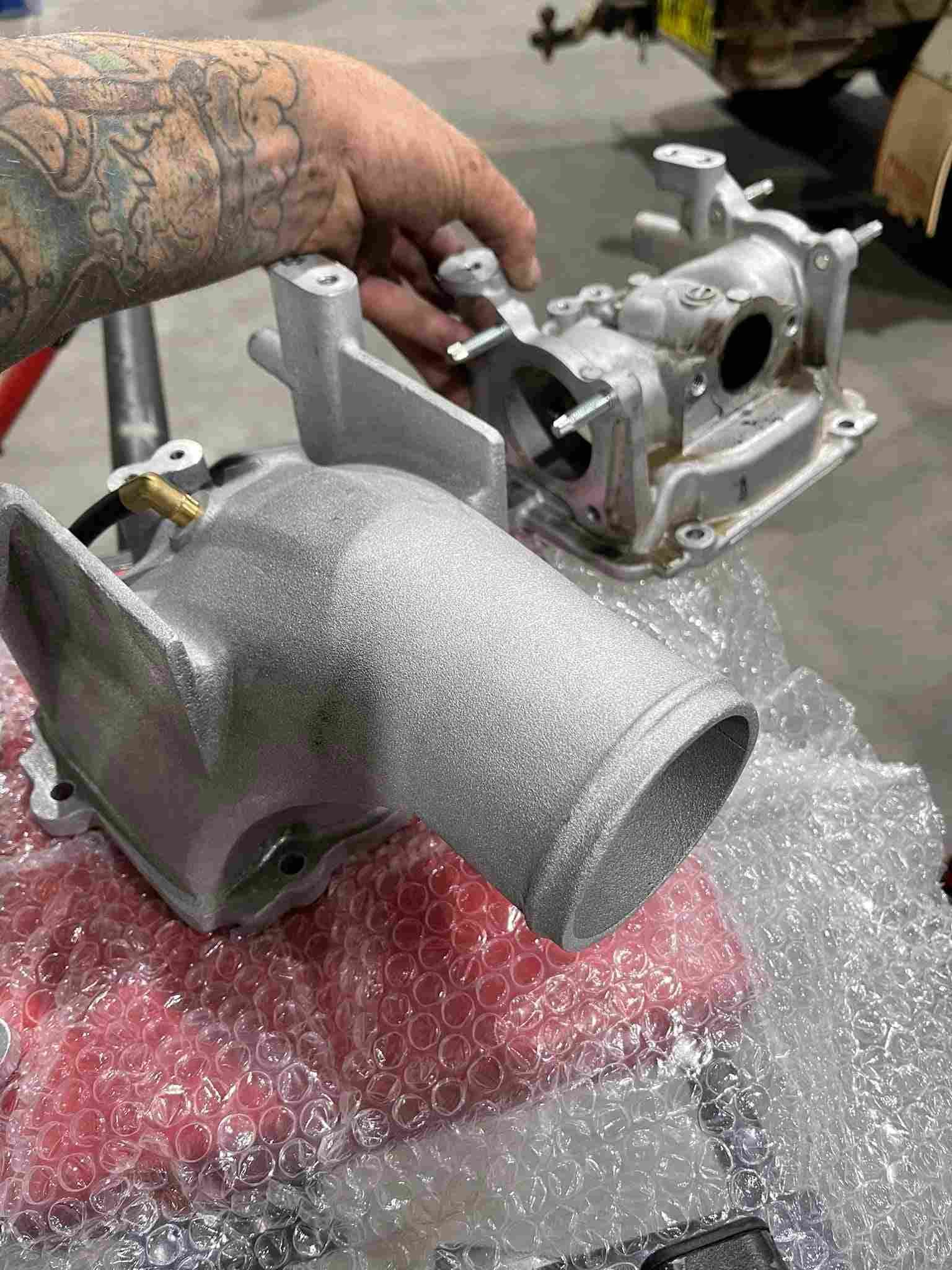 A Man With a Tattoo on His Arm is Working on a Piece of Metal — Outlaw Mechanical & Performance In Inverell, NSW