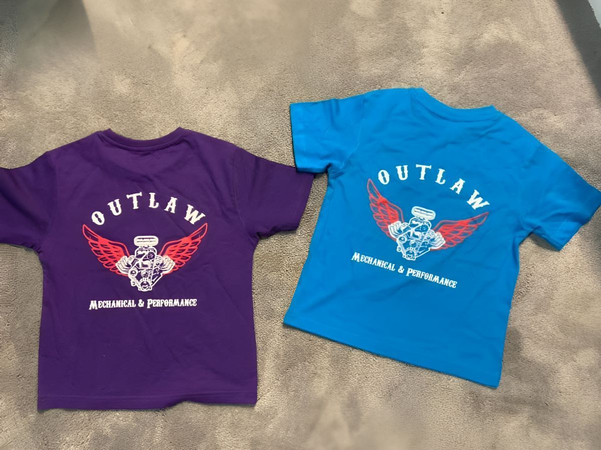 A purple and a blue outlaw t-shirt are on a carpet