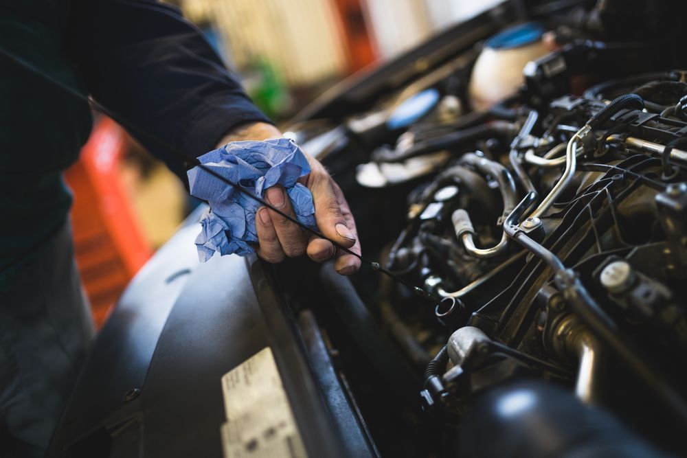 A Person is Checking the Oil Level of a Car Engine — Outlaw Mechanical & Performance In Inverell, NSW