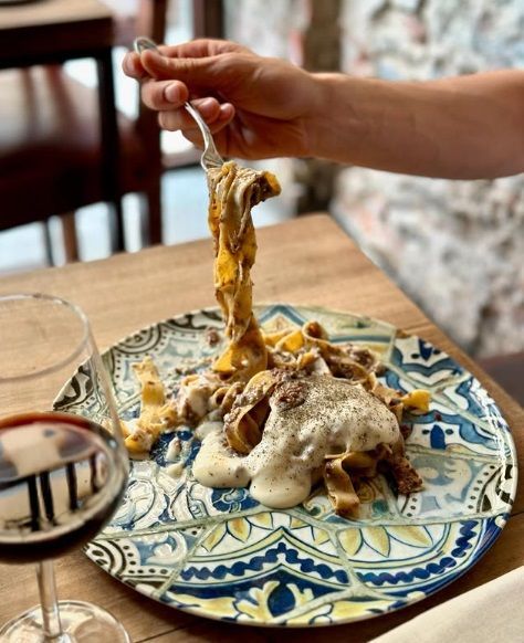 Pasta agli spinaci con formaggio grattugiato su un piatto decorato con motivi blu e bianchi, appoggiato su una superficie di legno.