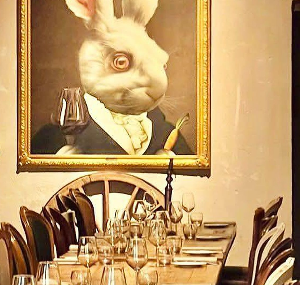 Piatto di pasta su un piatto decorato, guarnito con noci e salsa, su una superficie di legno.