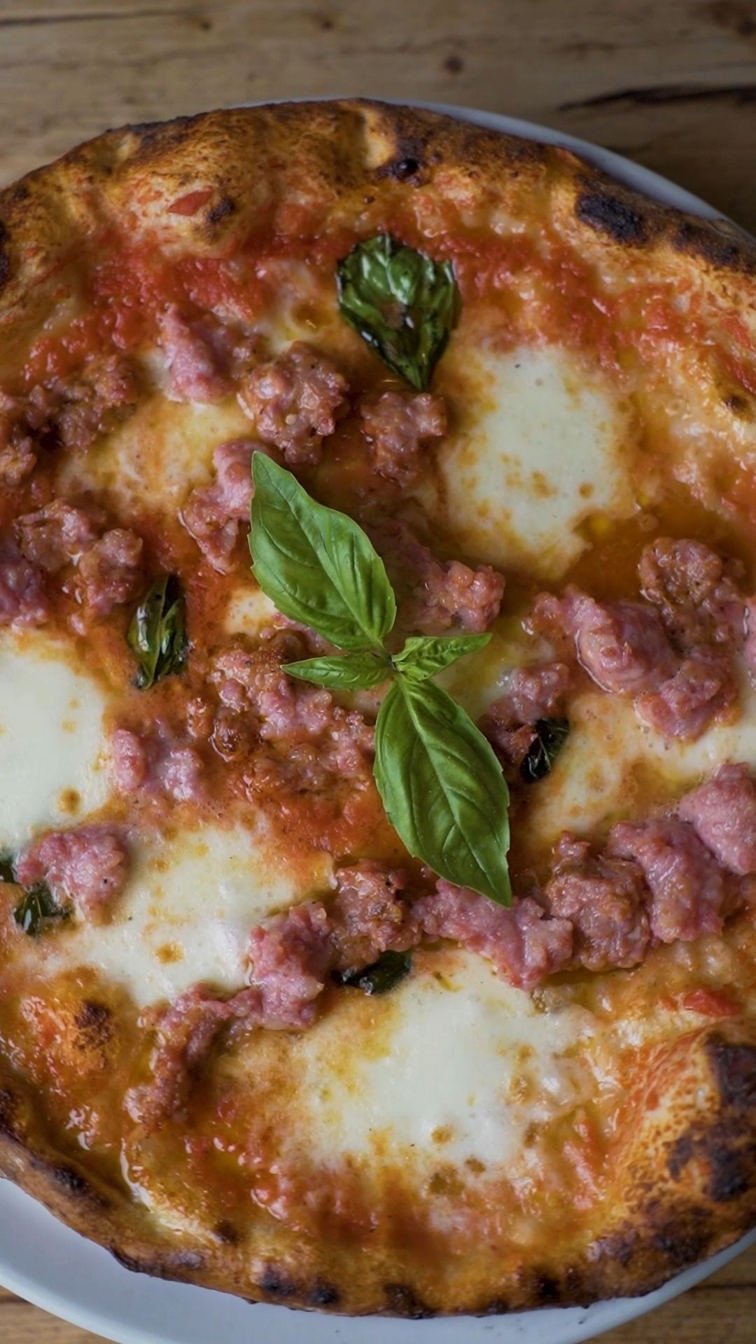 Pizza con salsa di pomodoro, salsiccia, mozzarella e basilico.