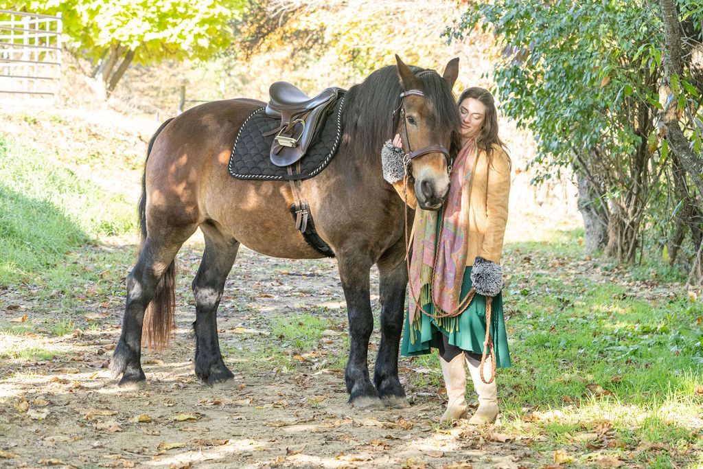 A woman is standing next to a horse with a saddle on it.