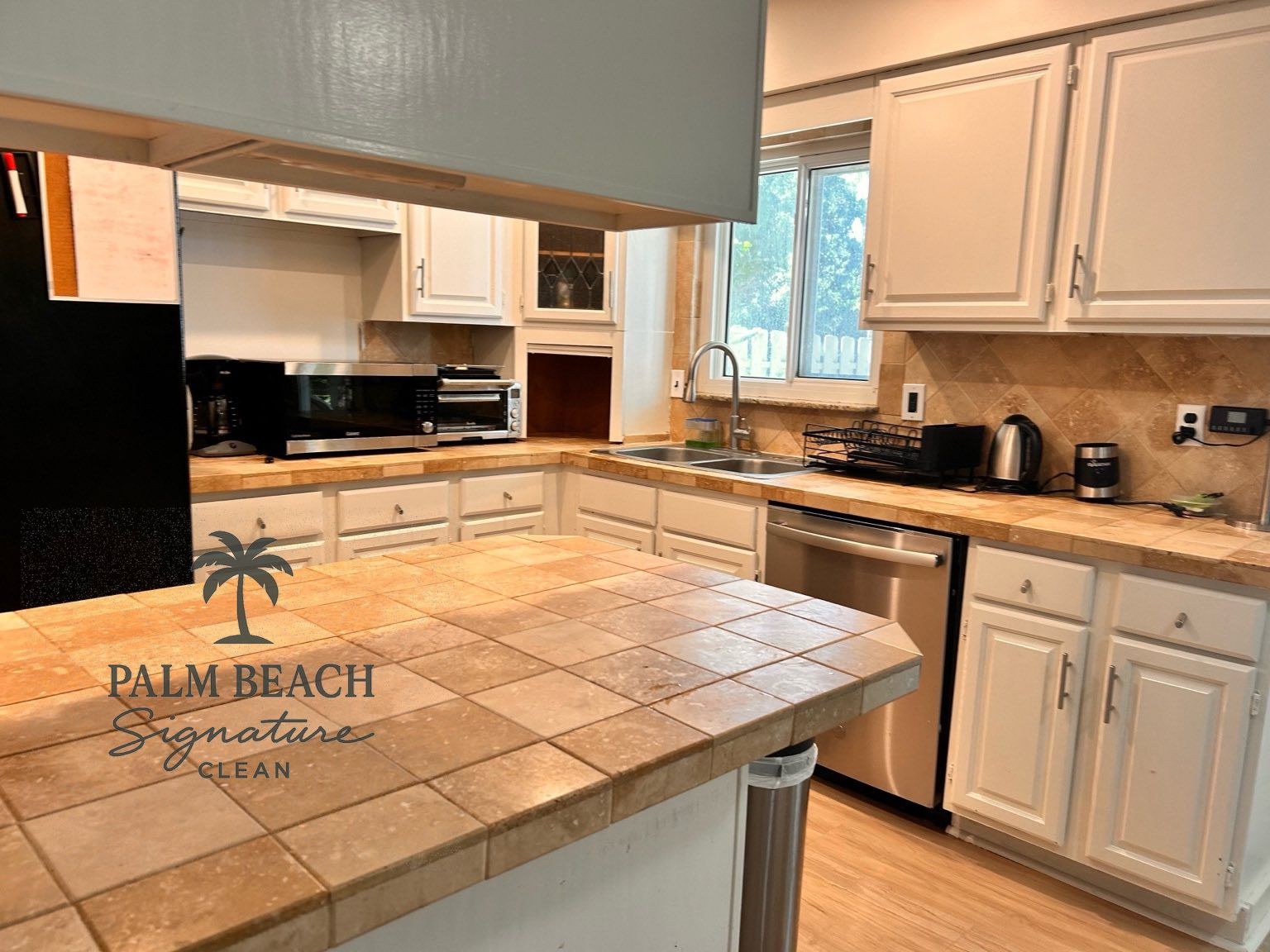 Kitchen with white cabinets, tile countertops, and stainless steel appliances.