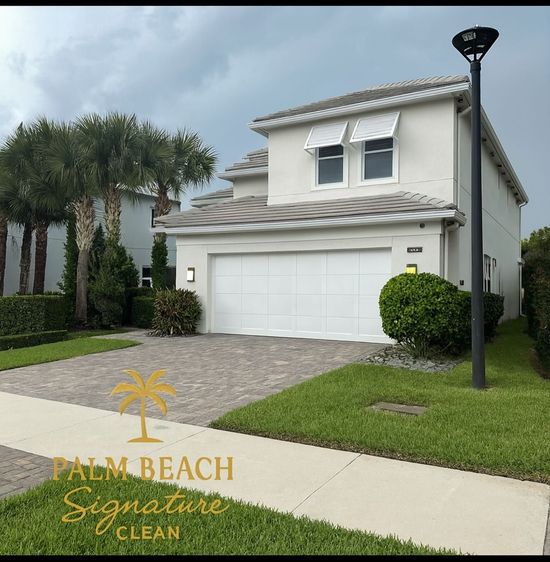 Two-story home with white garage, driveway, and landscaping in a cloudy setting.