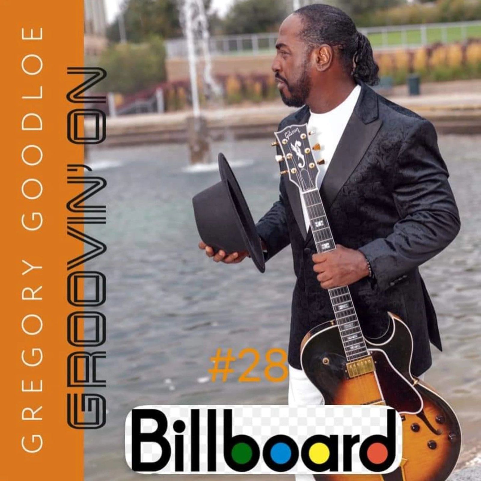 Gregory Goodloe holding guitar, ranked #28 on Billboard. Outdoors; fountain in background.