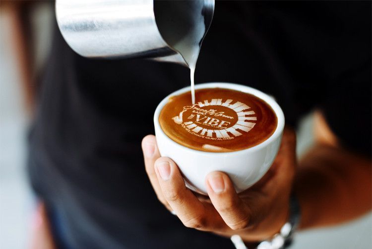 Barista pouring milk art on coffee with 