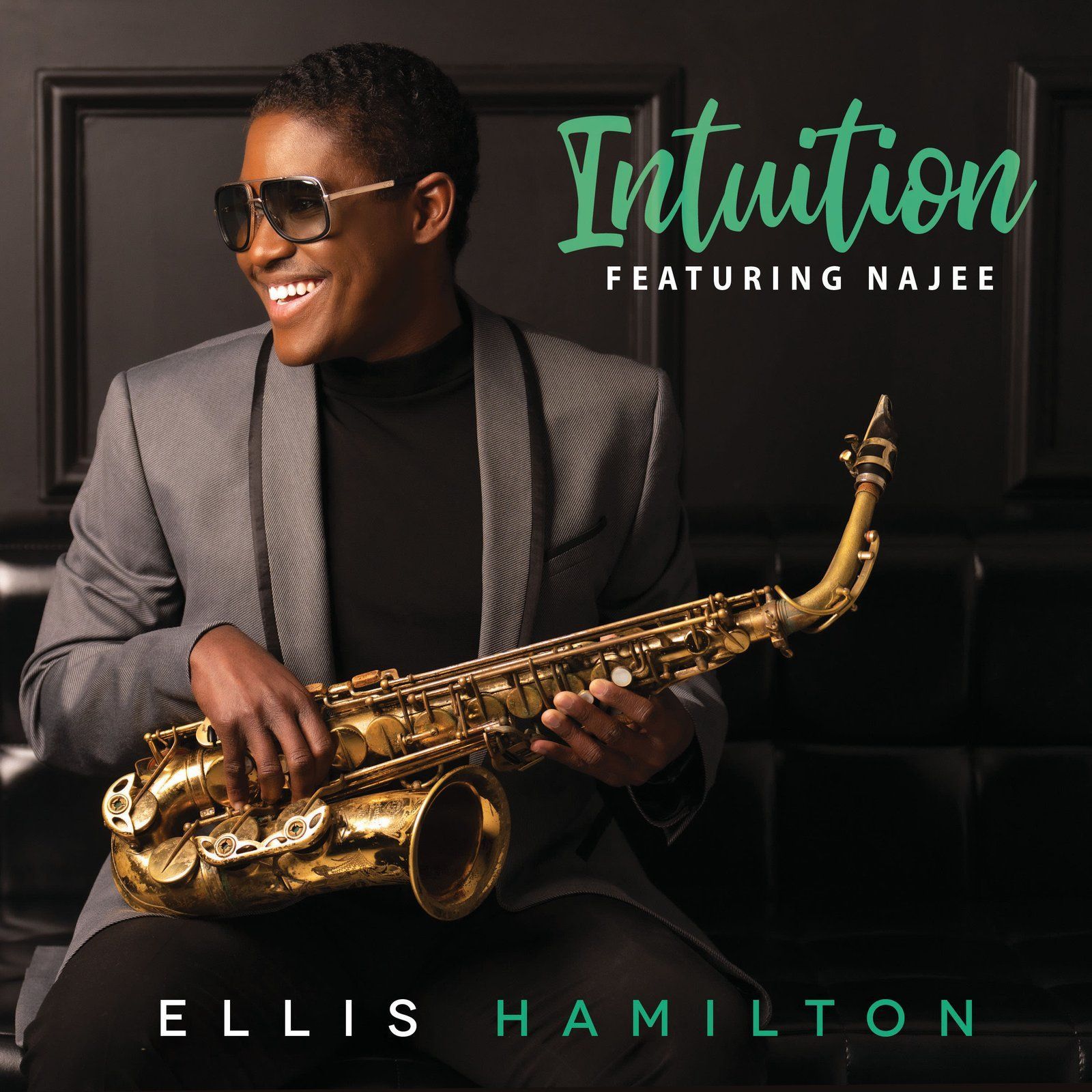 Ellis Hamilton smiles, holding a saxophone. He wears a gray suit and sunglasses. The album title, 