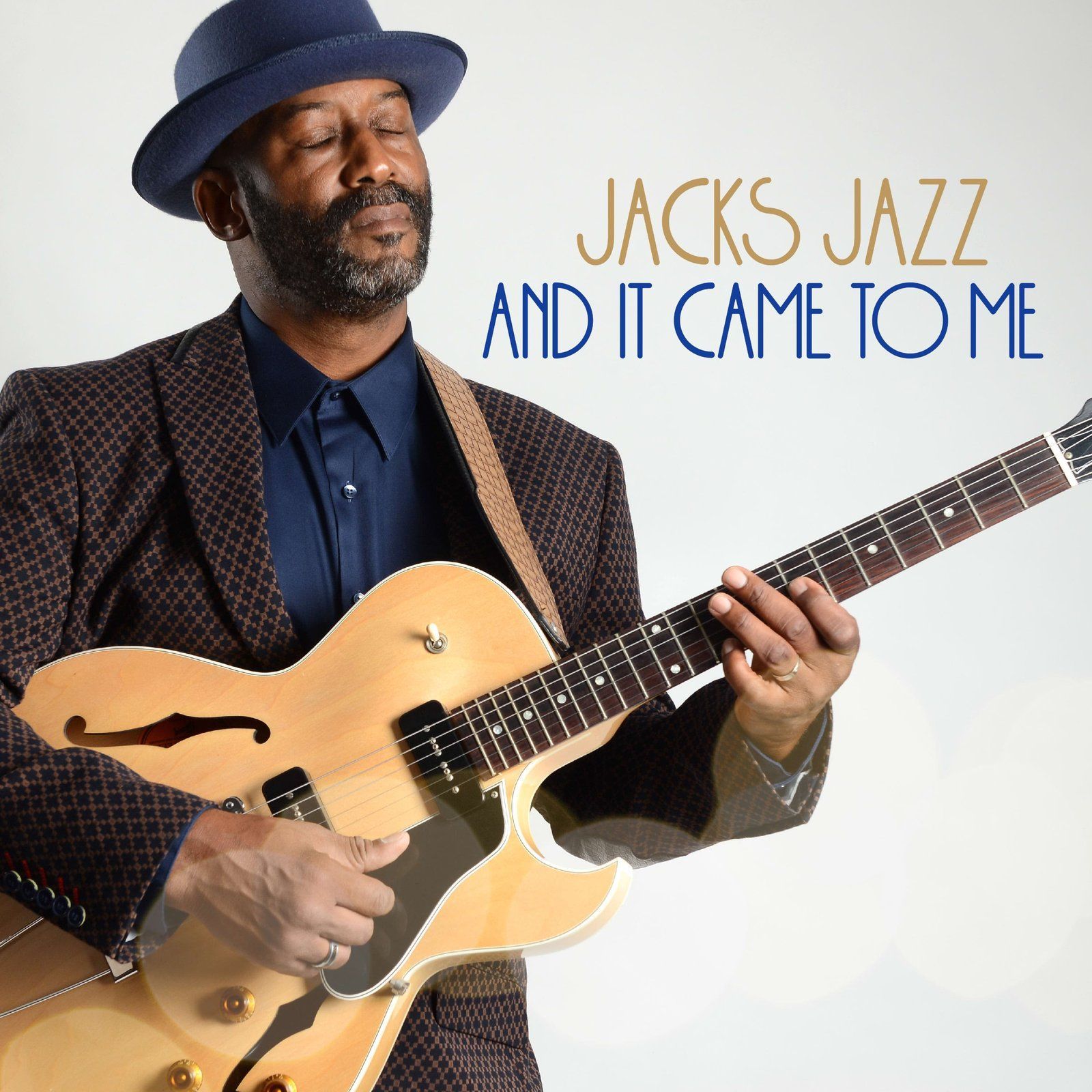 A man in a fedora plays a jazz guitar, album cover 