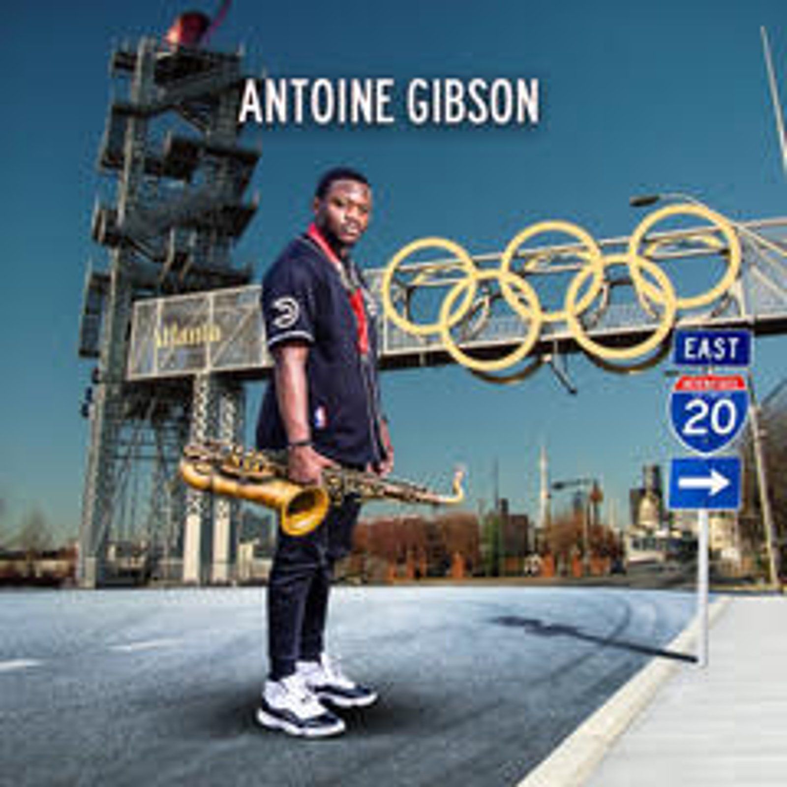 Antoine Gibson stands with saxophone near Atlanta Olympics sign and interstate 20.