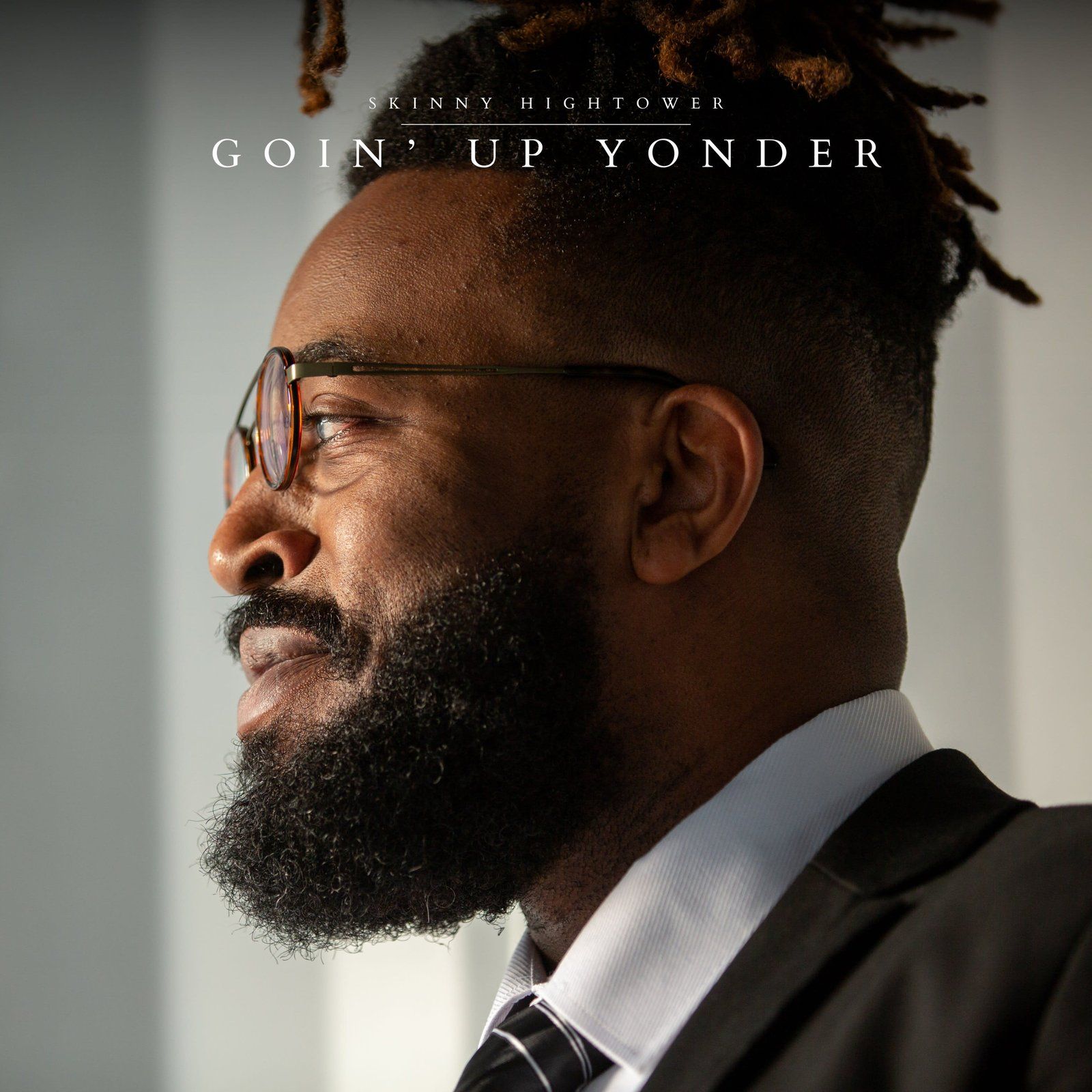 Man in a suit and glasses, looking out a window. Text: 