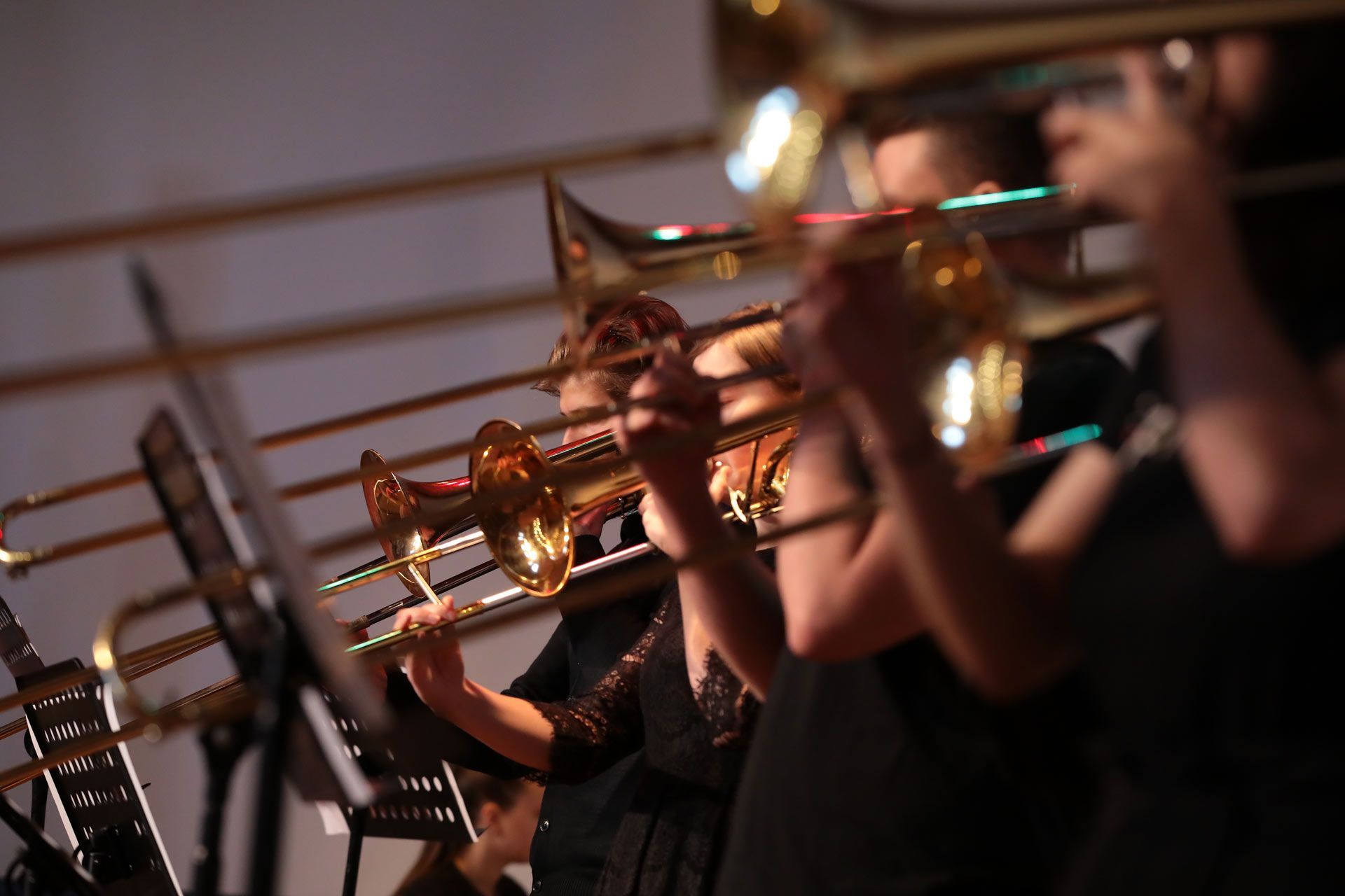 People playing trombones in a brightly lit performance.
