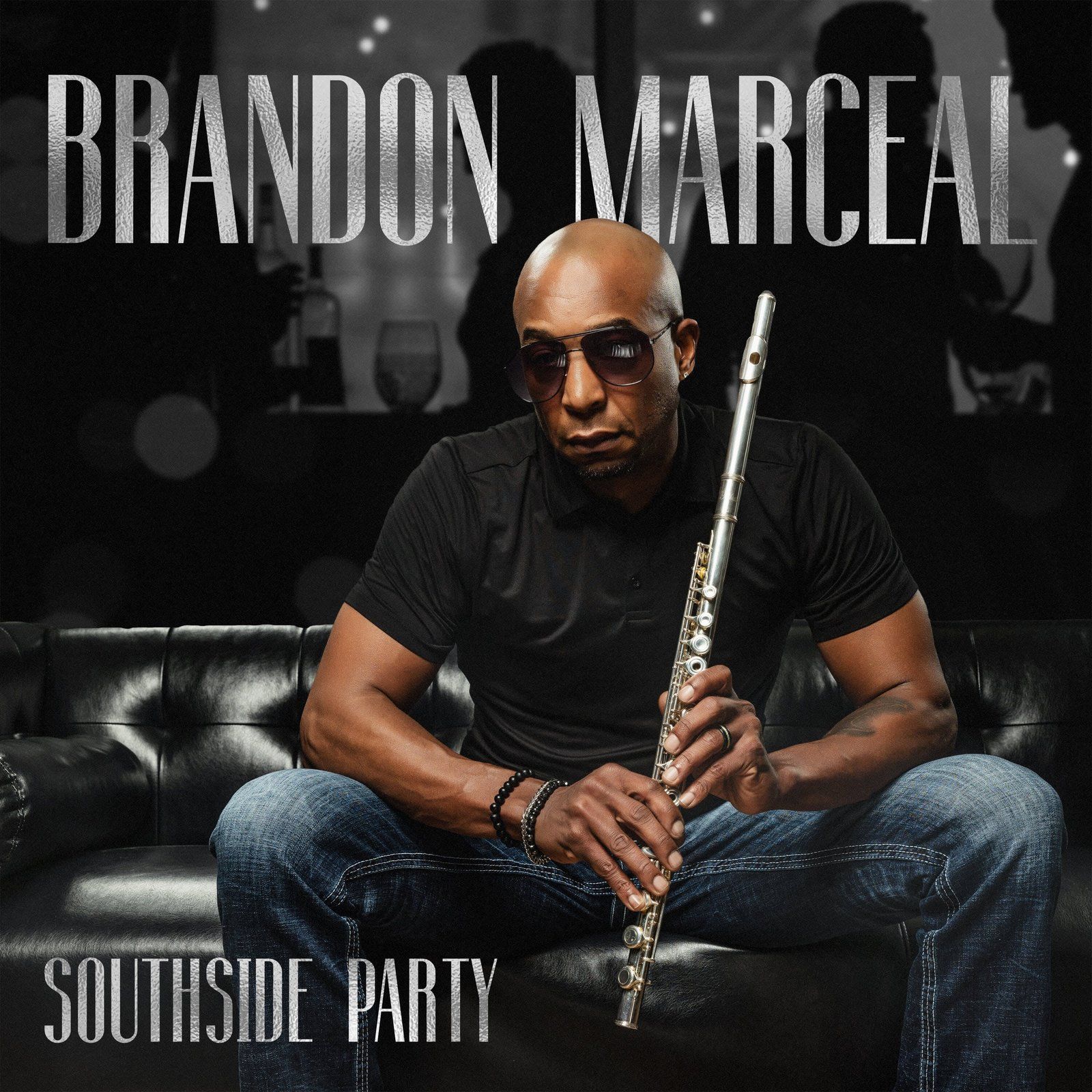 Brandon Marcel, musician, seated with flute, on a black couch. Album cover, Southside Party.