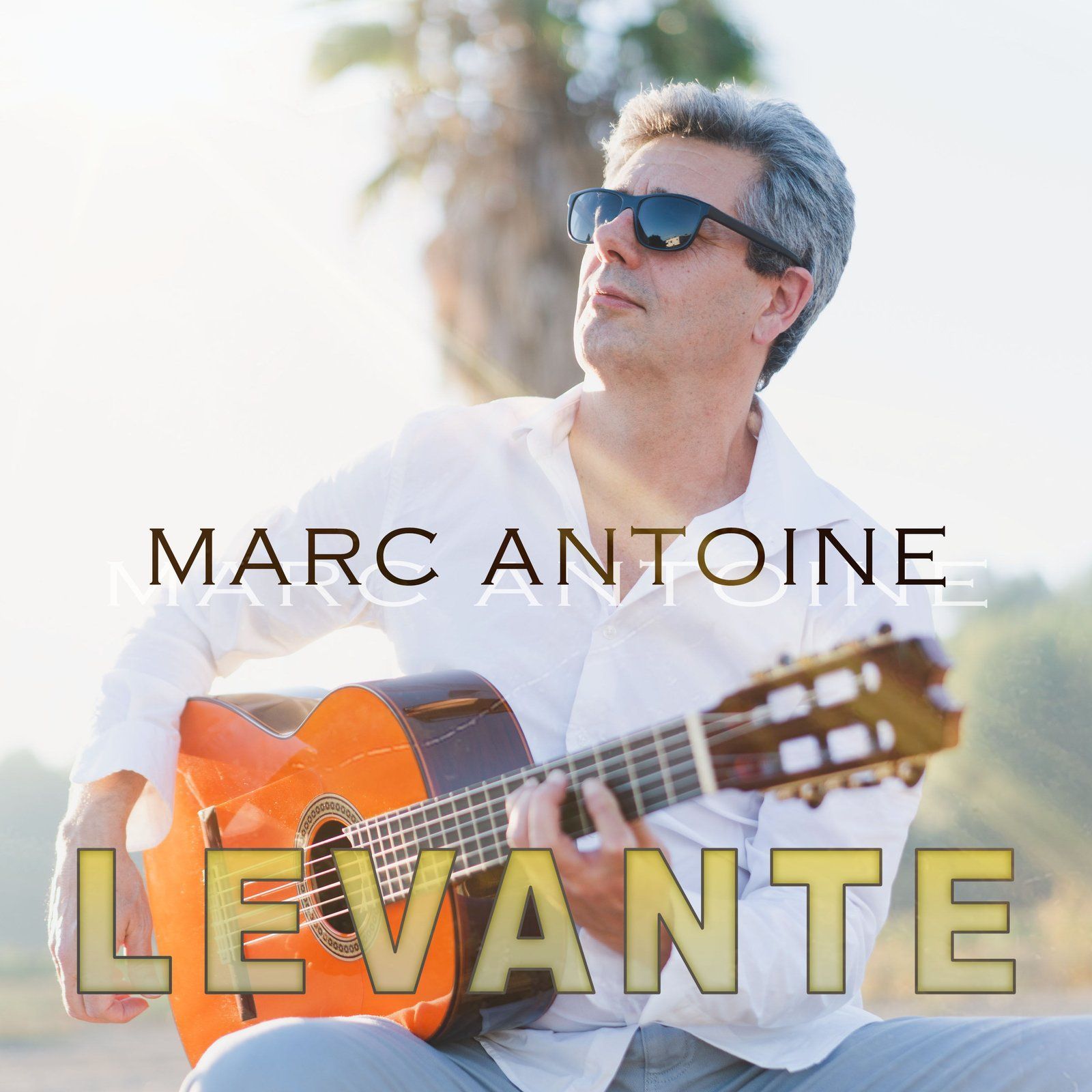 Marc Antoine playing acoustic guitar outdoors, wearing sunglasses. Album cover for 