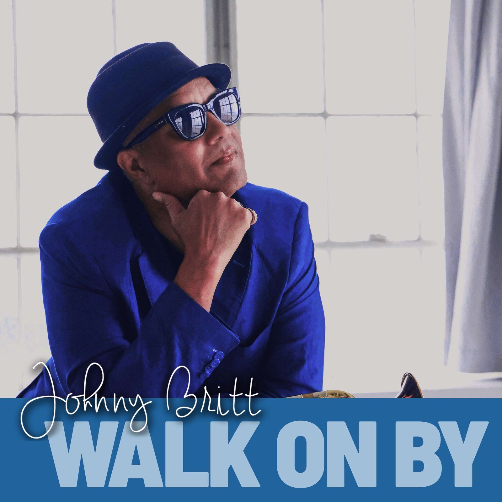 Johnny Britt, wearing a blue jacket, sunglasses, and hat, looks thoughtful. Text reads 