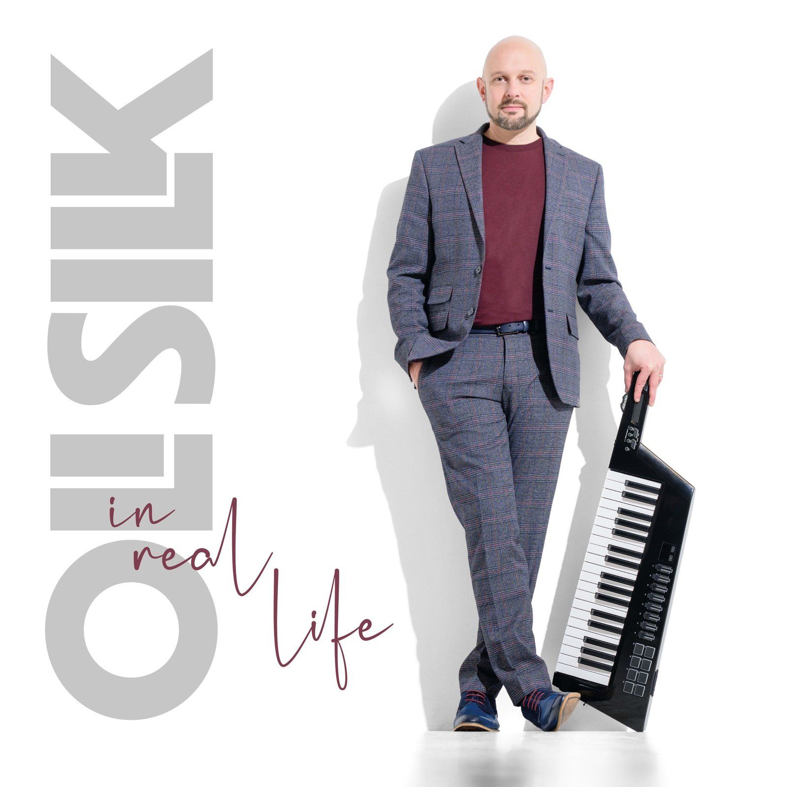 A man in a suit holds a keyboard; album cover for 