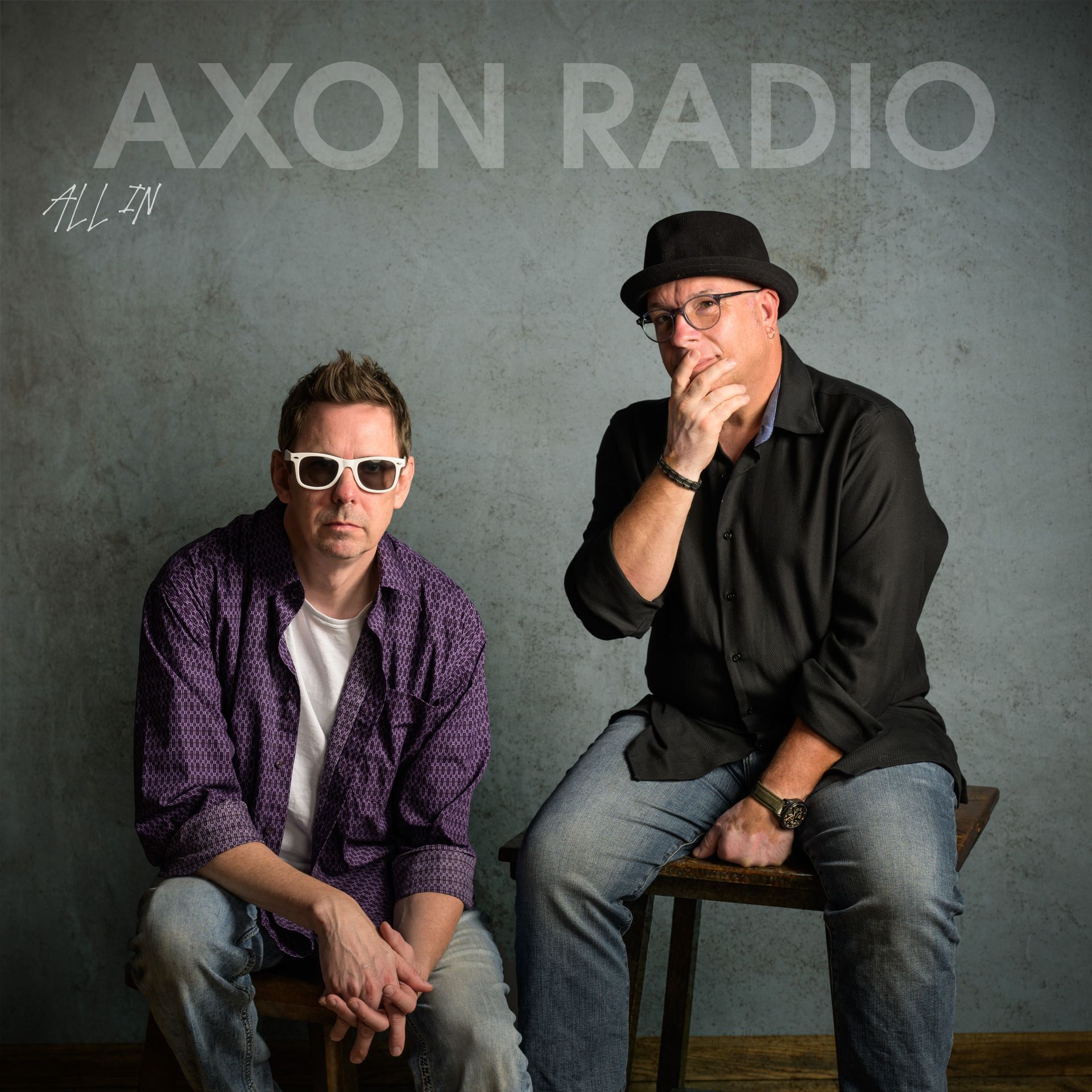 Two men, one in sunglasses, sitting near each other.