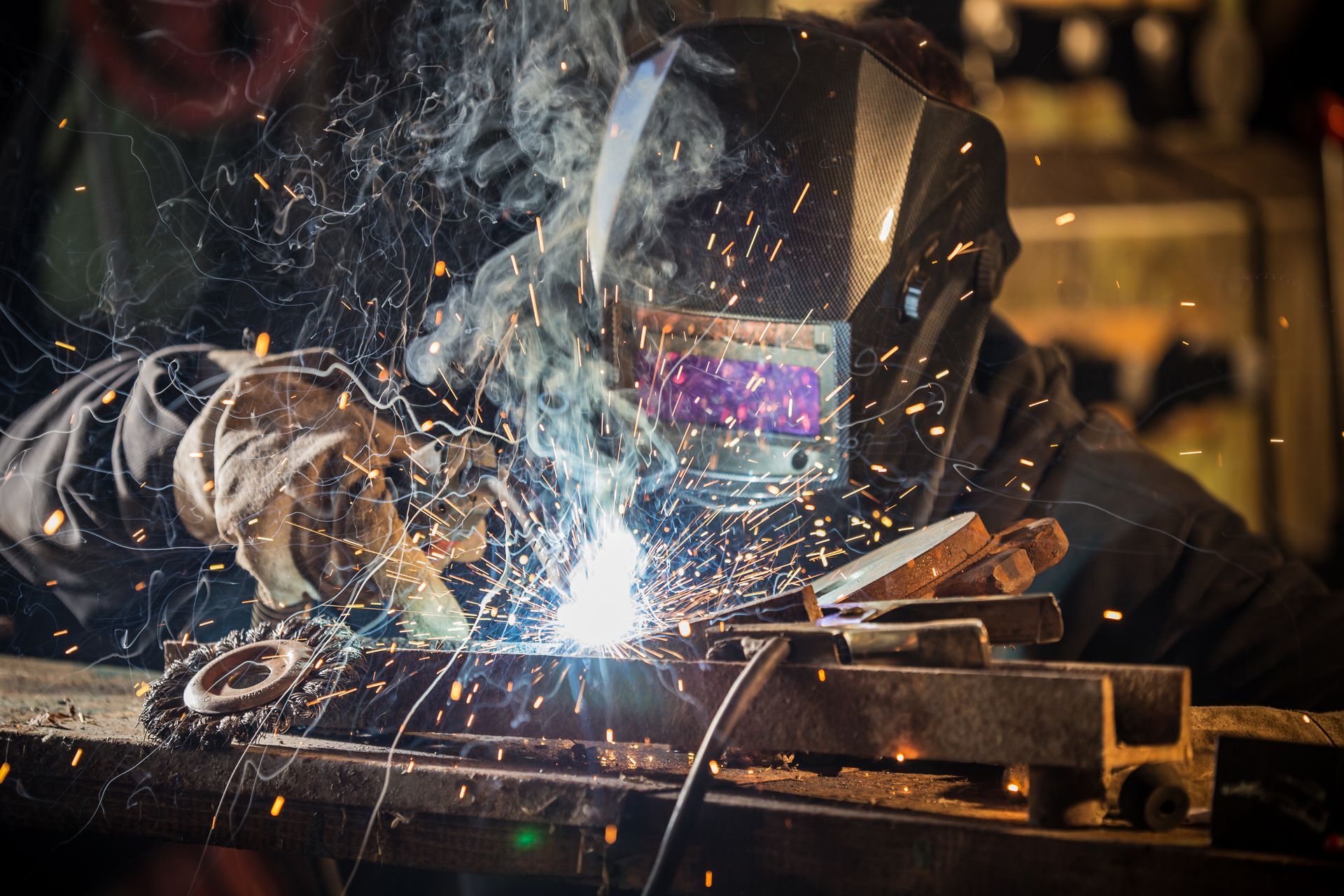 A man is welding a piece of metal in a factory.