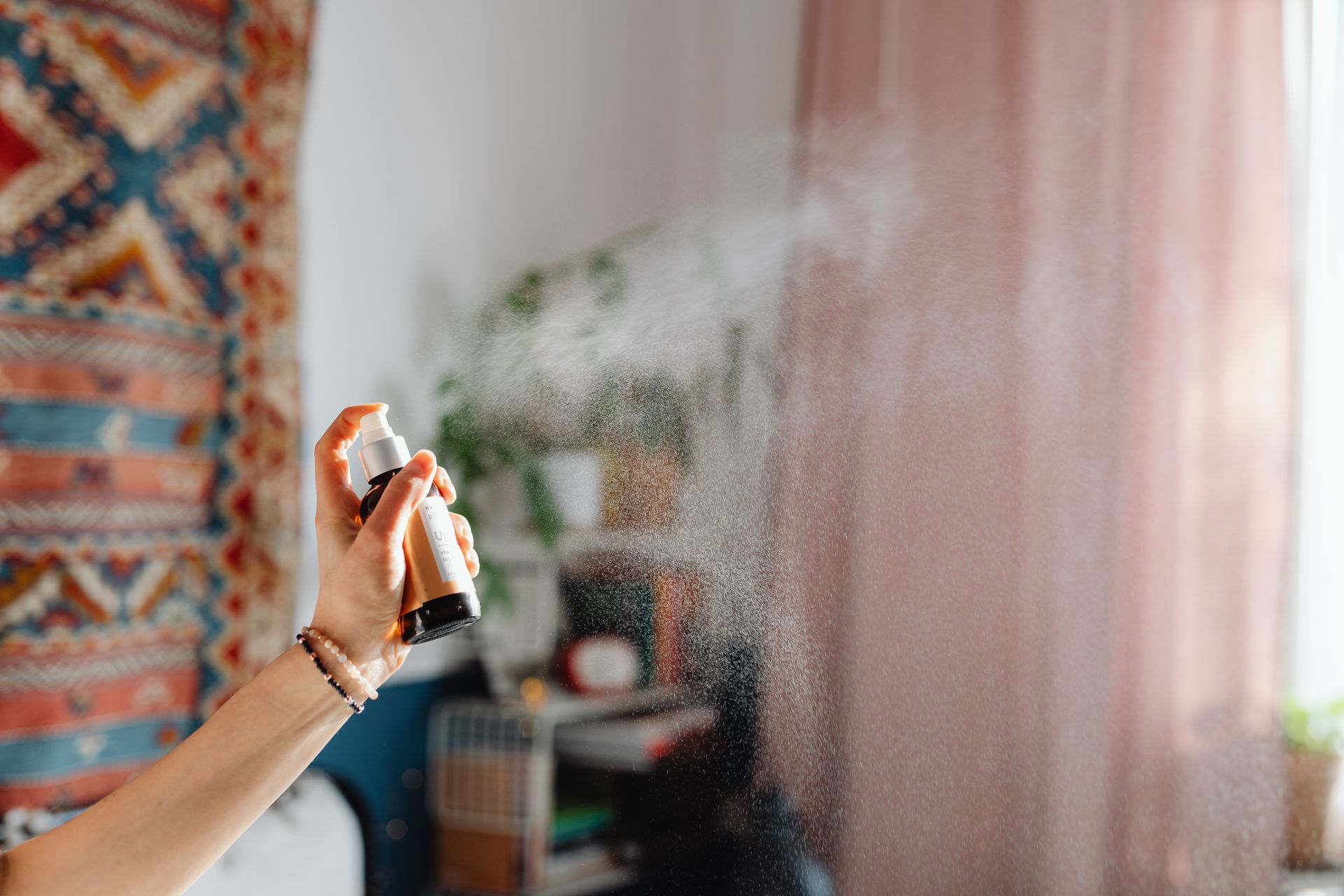 A woman is spraying a room with a spray bottle.