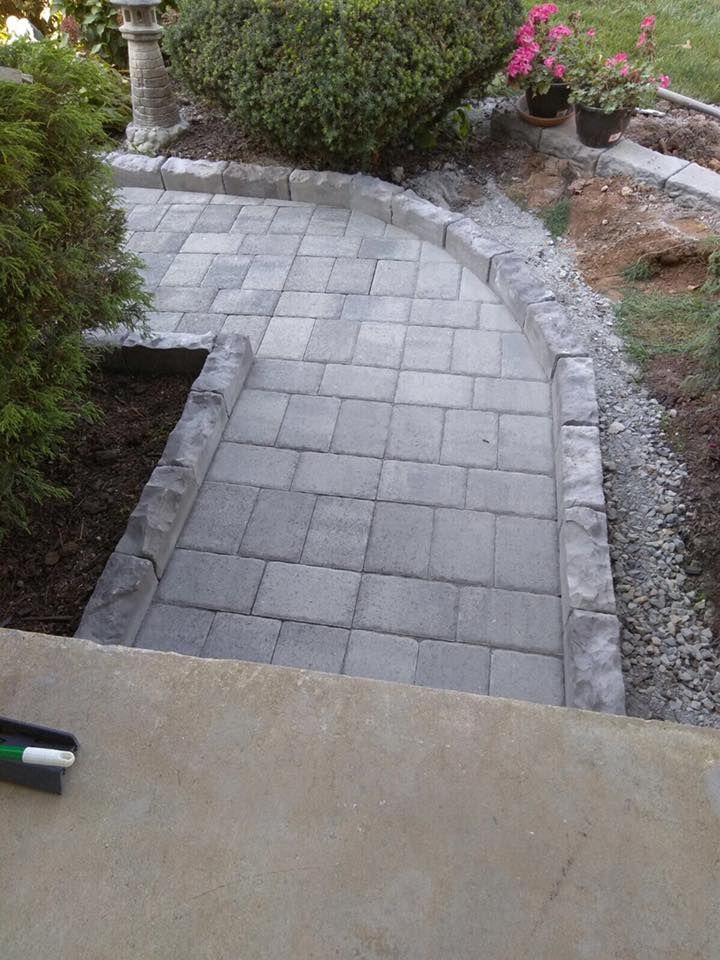A brick walkway is being built in a garden.
