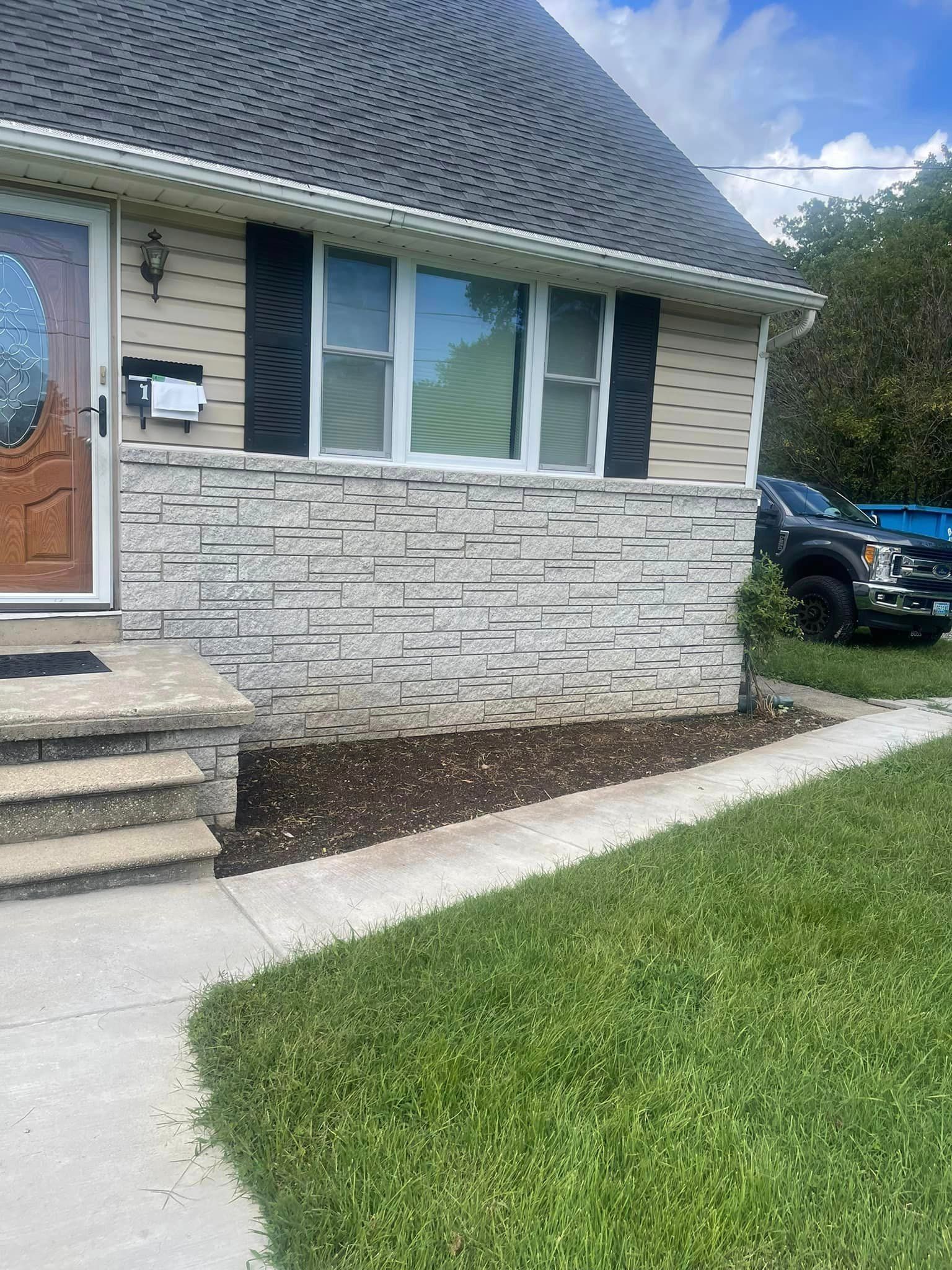 A blue truck is parked in front of a brick house.