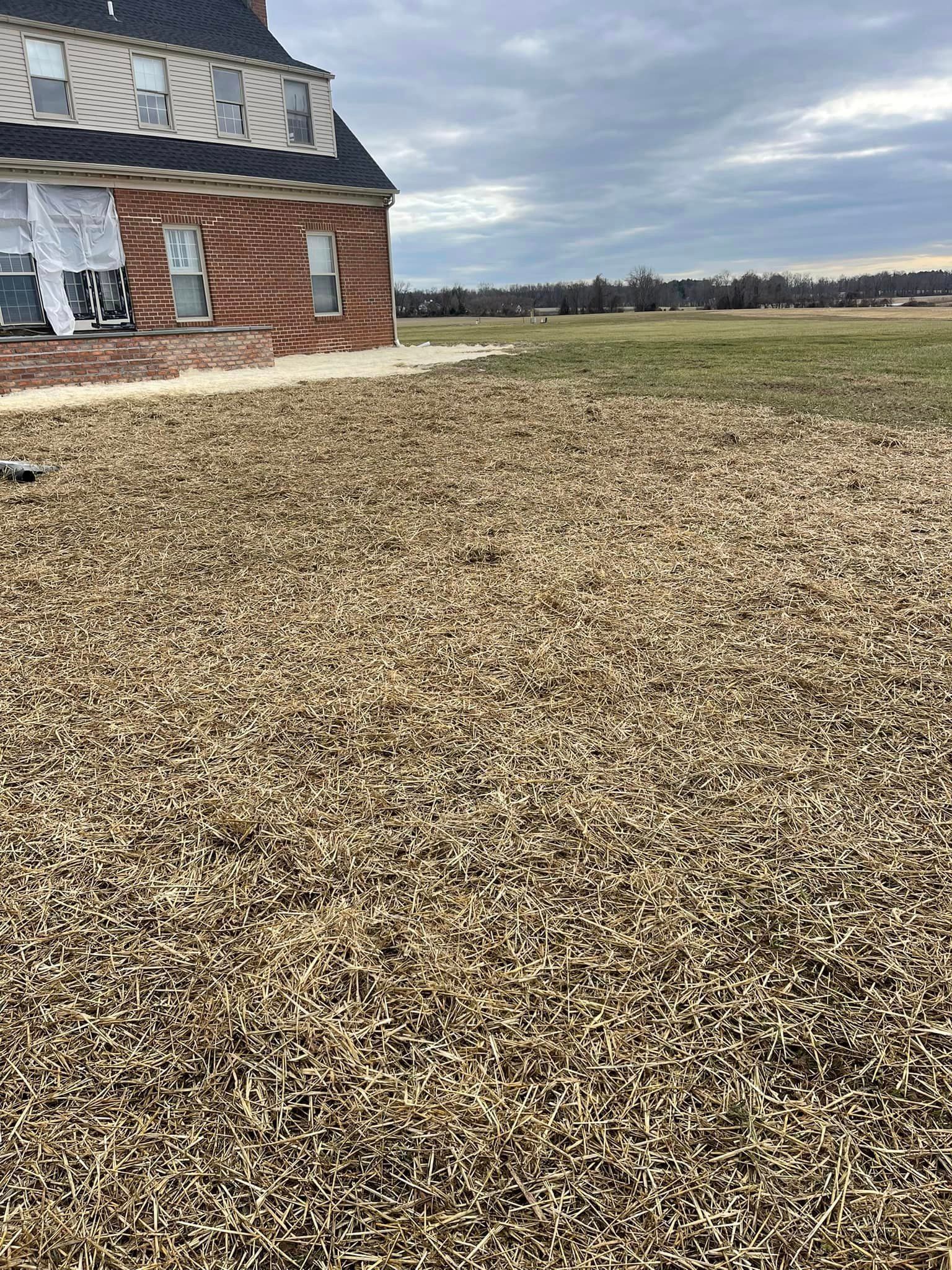 A brick house is sitting in the middle of a field.