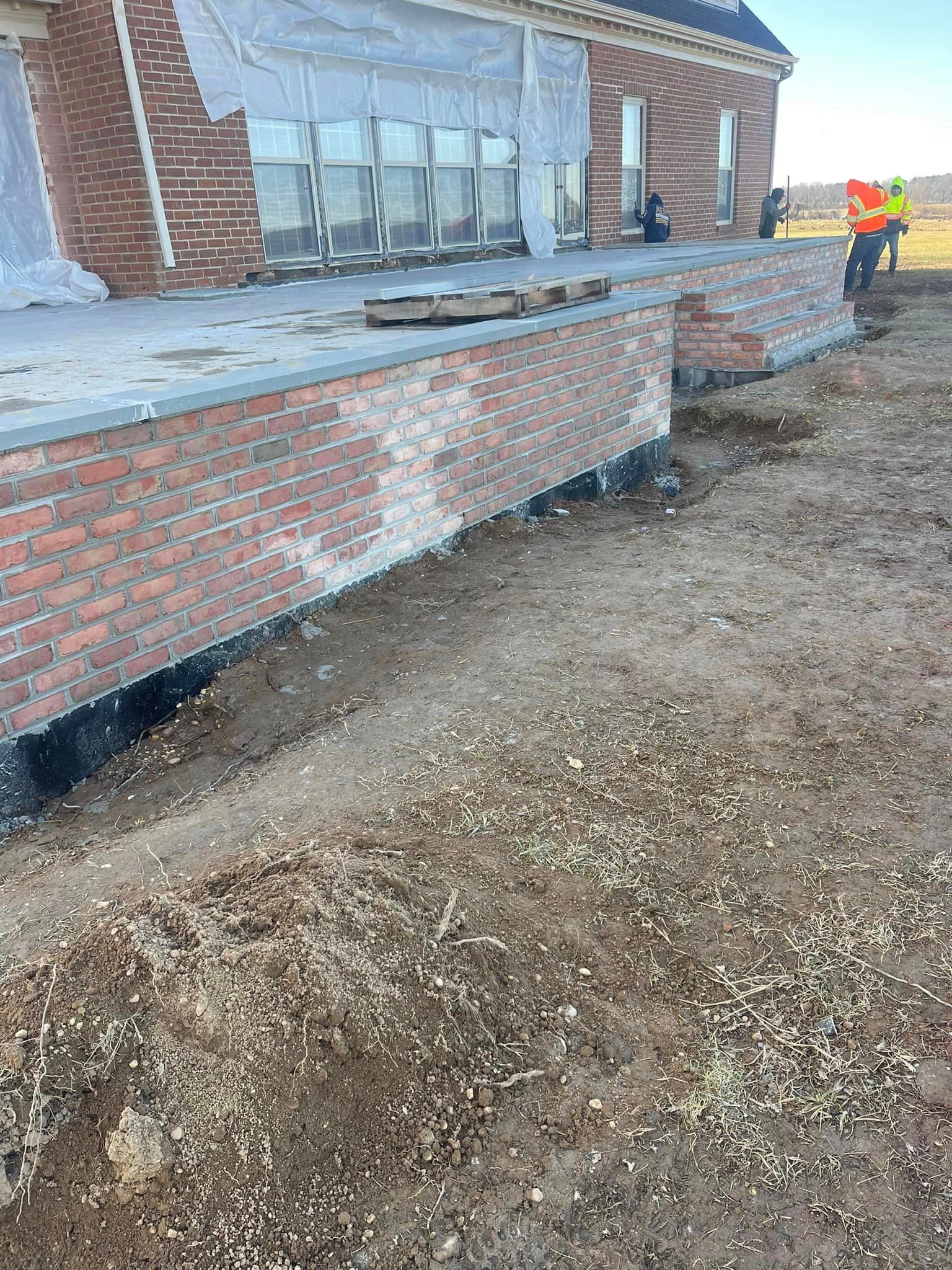A man is digging a hole in front of a brick building.