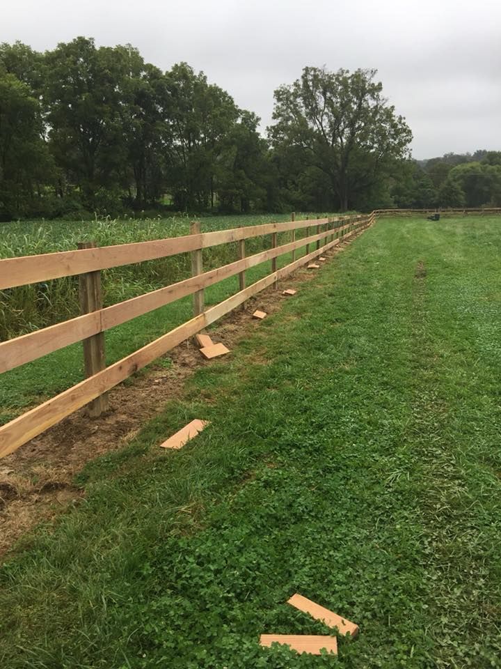 A wooden fence is being built in a grassy field.