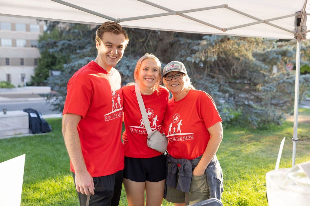 Teenage brother and sister with their mother, wearing red volunteer shirts at CDF event.