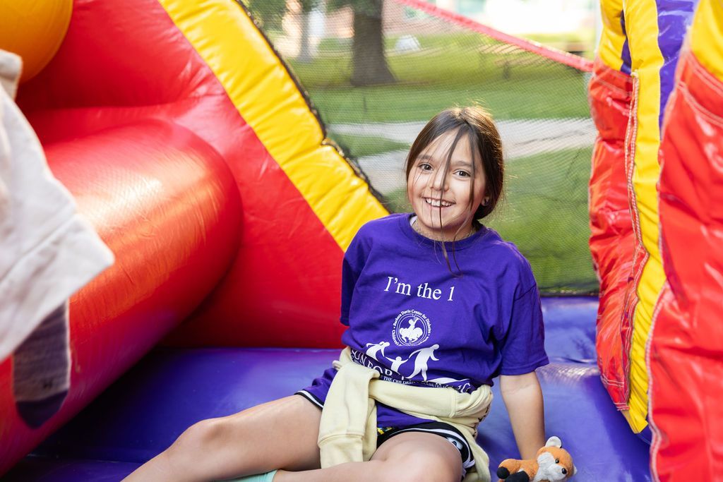 Girl in purple "I'm the 1" t-shirt playing on bouncy castle in Kids Fun Zone.
