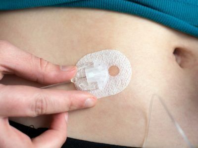 A person is holding a needle in their stomach.