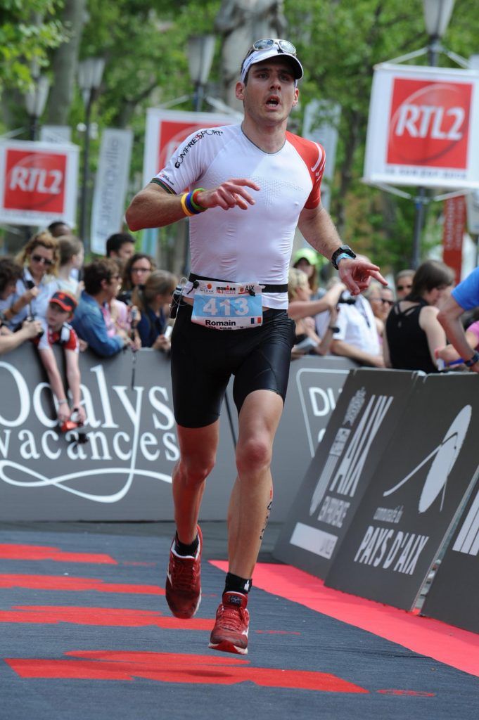 A man is running a marathon in front of a crowd.