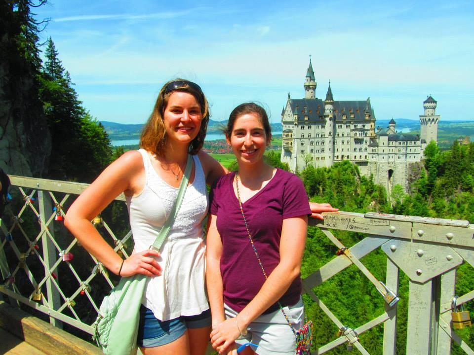 Two women are posing for a picture in front of a castle