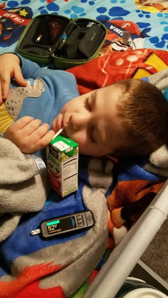 A young boy is sleeping on a bed with a box of milk and a thermometer.