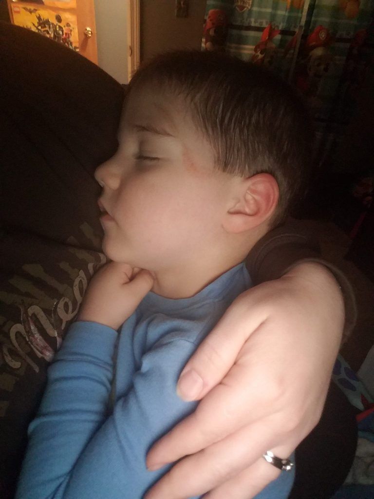A little boy is sleeping in a person 's arms.