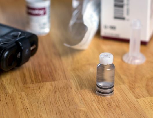 A small bottle of liquid is sitting on a wooden table.