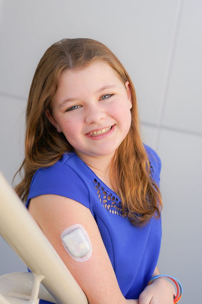 Girl with CGM device on her arm smiling for the camera