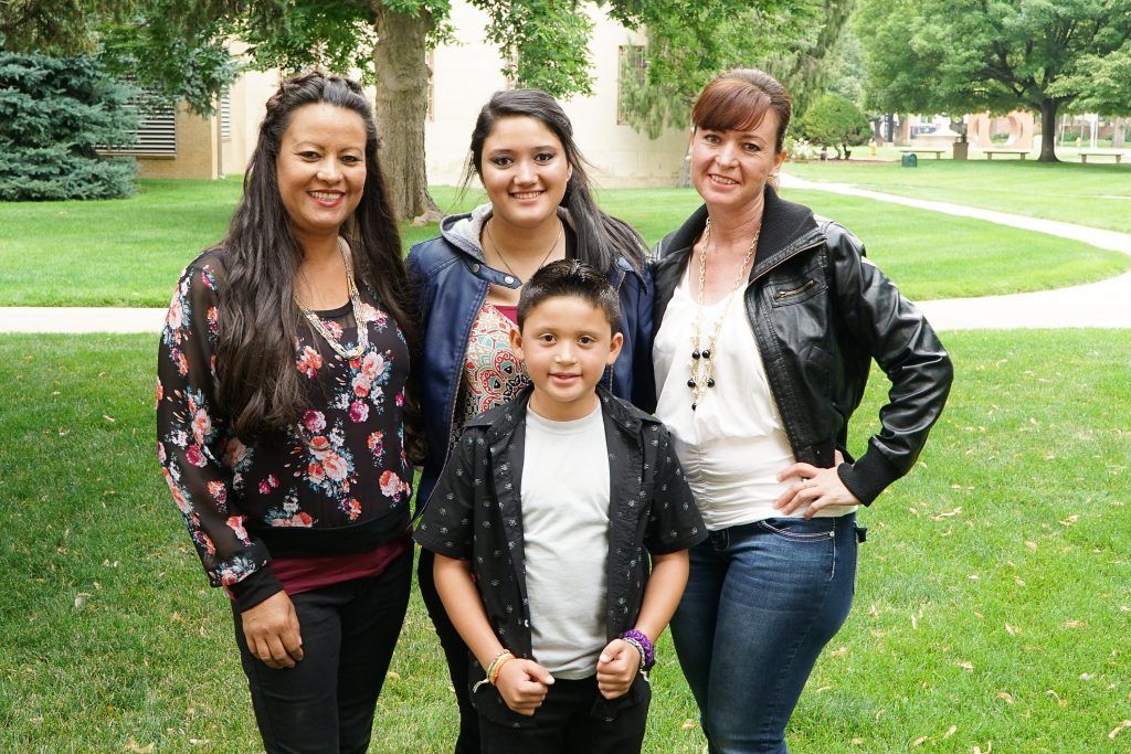 Three women and a boy are posing for a picture in a park.