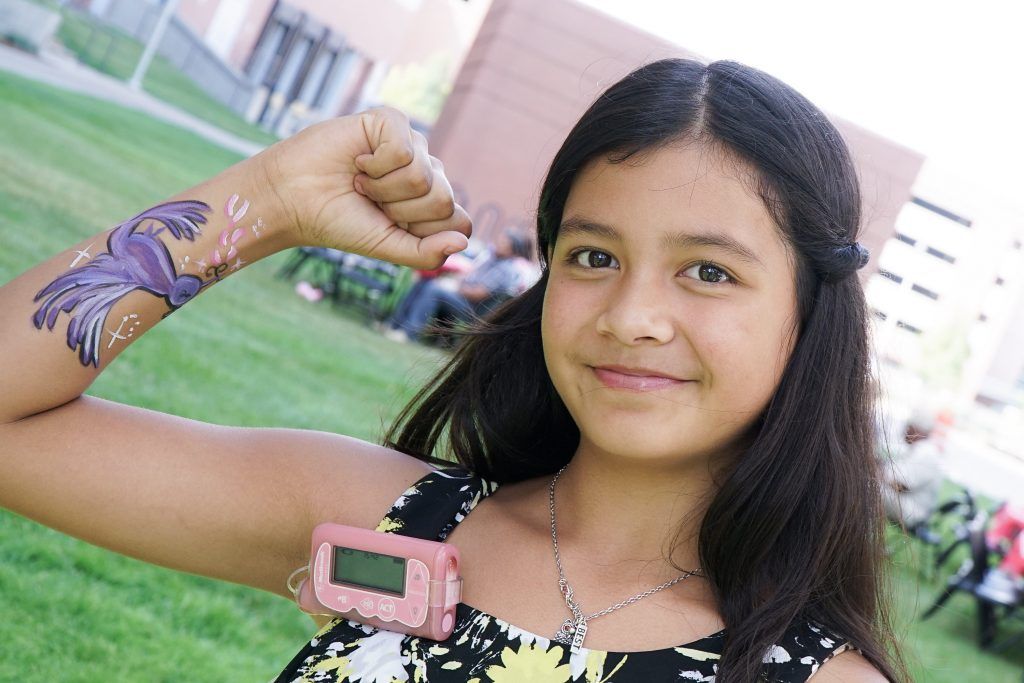 A young girl with a tattoo on her arm is wearing a pink watch.