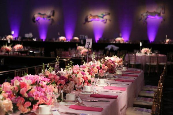 A long table with pink flowers on it is set for a wedding reception.