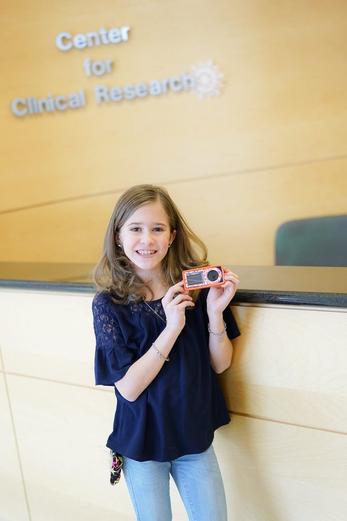 A young girl is holding a camera in front of the center for clinical research