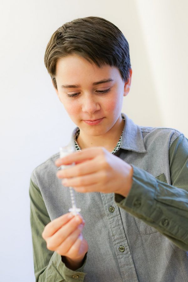 A young boy is holding a syringe in his hands