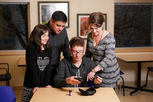 A group of people standing around a table looking at a phone